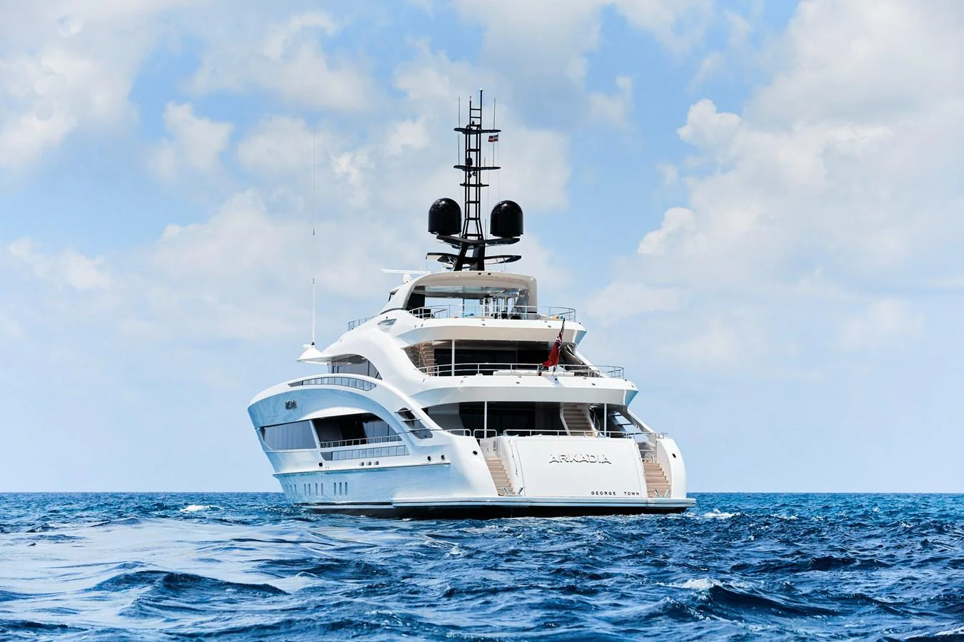 A luxurious yacht is anchored on the open sea under a partly cloudy sky. aboard ARKADIA Yacht for Sale