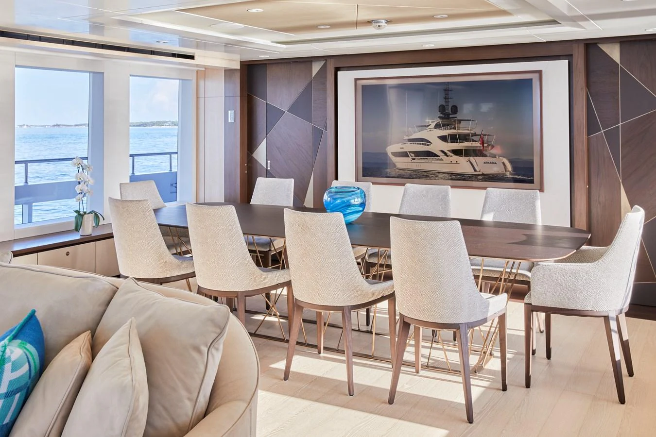 The yacht's dining area features a large table with elegant chairs and a beautiful view of the sea through the windows. aboard ARKADIA Yacht for Sale