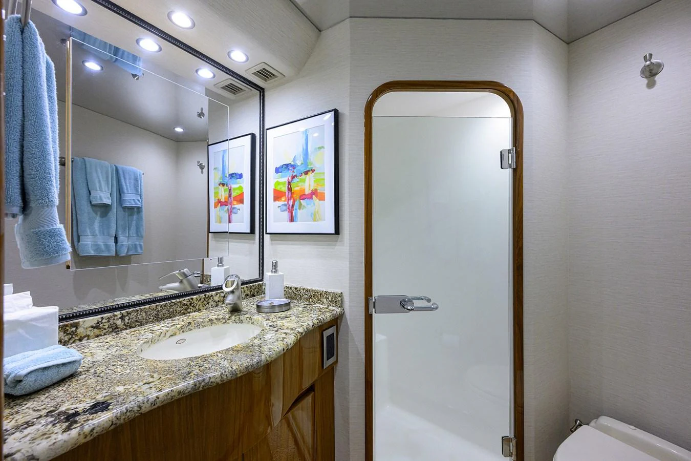 A modern yacht bathroom featuring a granite countertop and a glass shower door. aboard WASABI Yacht for Sale