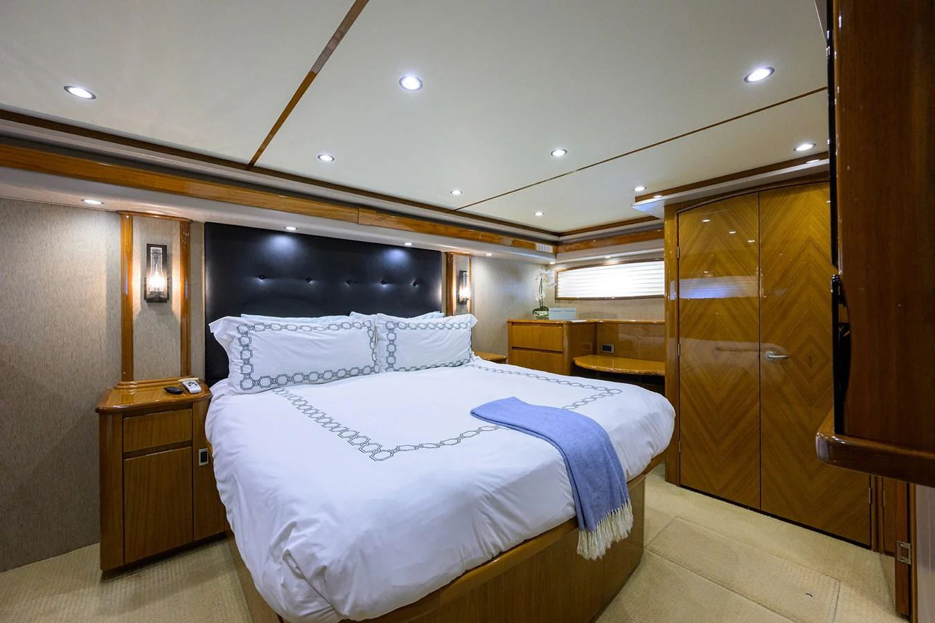 The master stateroom features a spacious bed with elegant bedding and warm wood finishes. aboard WASABI Yacht for Sale