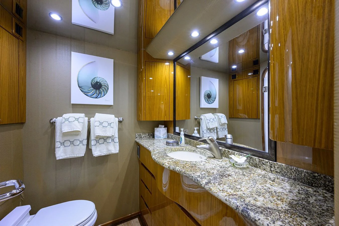 The yacht's bathroom features elegant wood cabinetry, a granite countertop, and modern fixtures. aboard WASABI Yacht for Sale