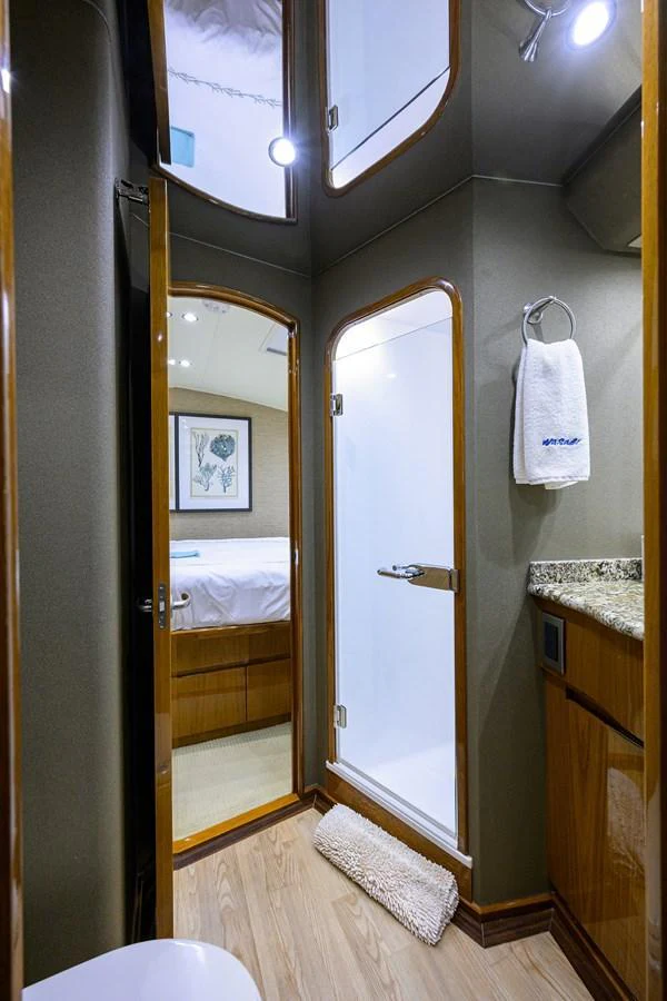 The yacht's bathroom features a modern shower, elegant wood finishes, and a granite countertop. aboard WASABI Yacht for Sale