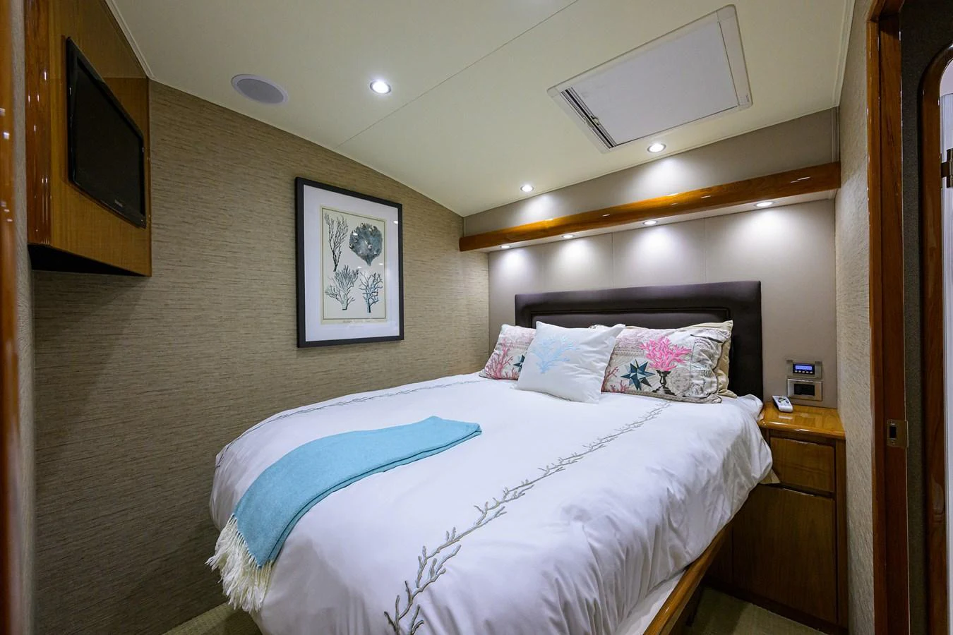 A cozy stateroom featuring a comfortable bed with decorative pillows and a framed artwork on the wall. aboard WASABI Yacht for Sale