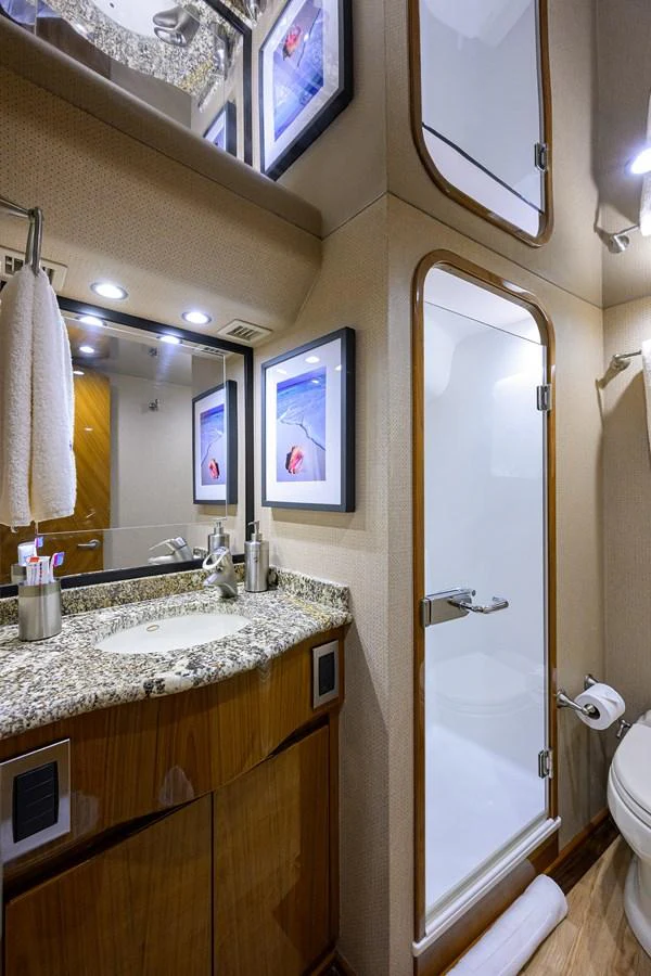 The yacht's bathroom features a sleek design with a granite countertop and a glass-enclosed shower. aboard WASABI Yacht for Sale