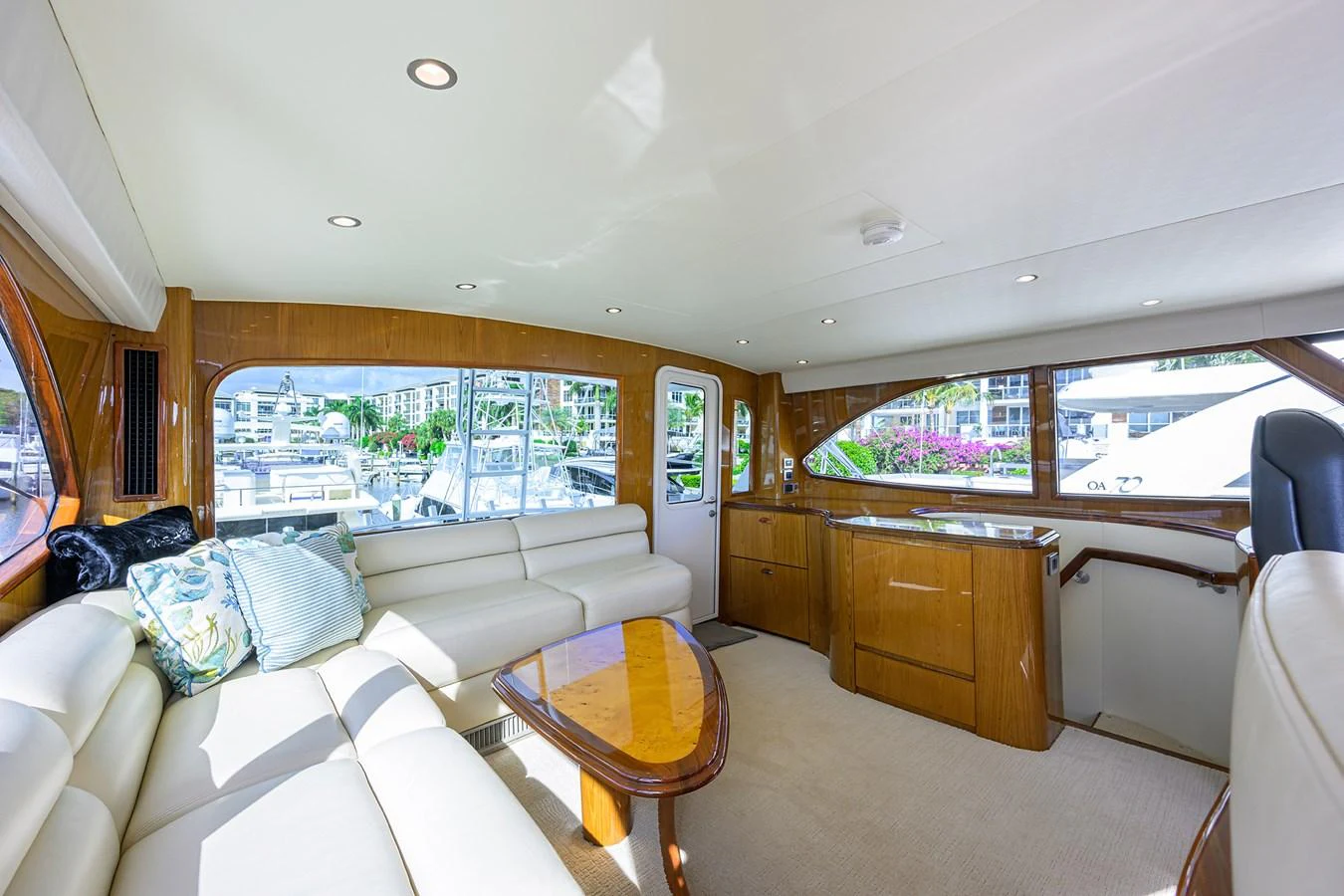 The salon features a spacious seating area with large windows offering a view of the marina. aboard WASABI Yacht for Sale