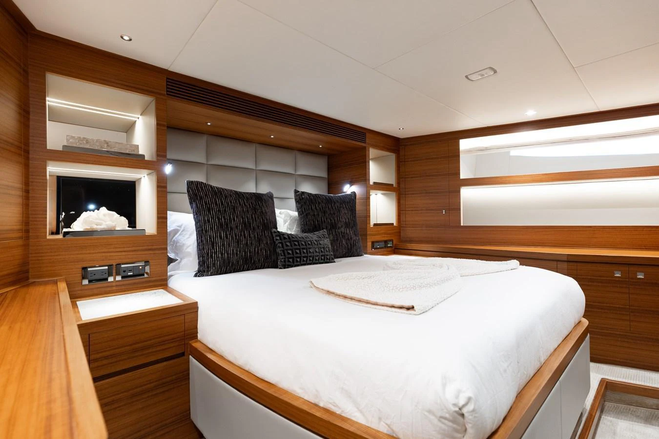 The stateroom features a luxurious bed with plush pillows and elegant wooden accents. aboard NEX-T Yacht for Sale