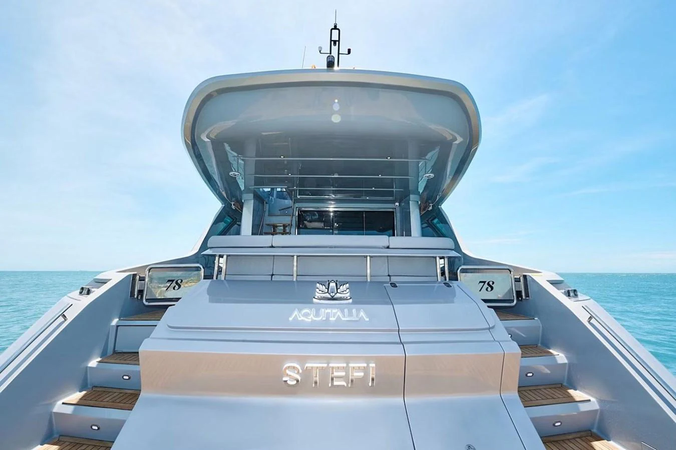 The yacht's stern showcases a sleek design with a spacious swim platform and inviting steps leading up to the deck. aboard 7809 Yacht for Sale