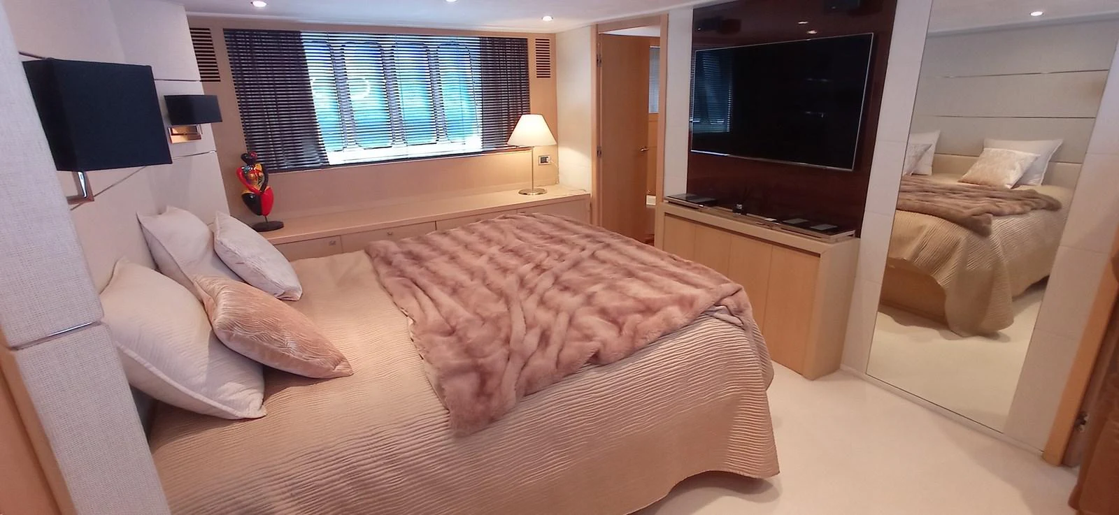 The stateroom features a cozy bed with plush bedding, a flat-screen TV, and ample natural light from the windows. aboard SFYFALL Yacht for Sale