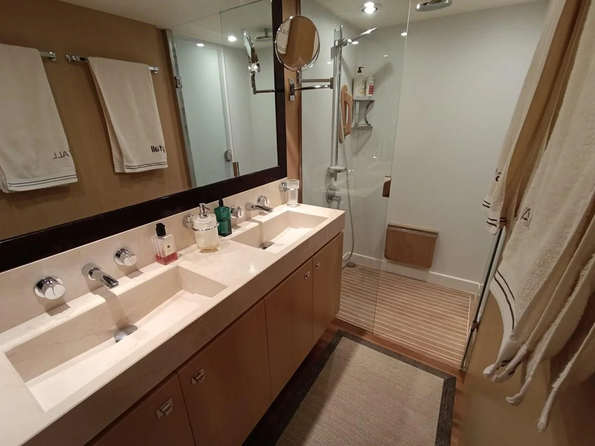 The yacht's bathroom features a double sink vanity and a spacious glass-enclosed shower. aboard SFYFALL Yacht for Sale