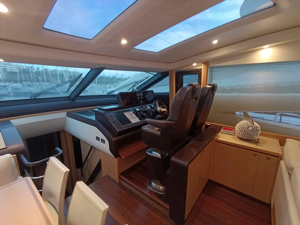 The helm station features luxurious seating and state-of-the-art navigation equipment, bathed in natural light from overhead skylights. aboard SFYFALL Yacht for Sale