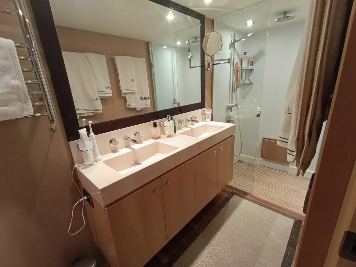 The yacht's bathroom features a double sink vanity and a spacious glass-enclosed shower. aboard SFYFALL Yacht for Sale