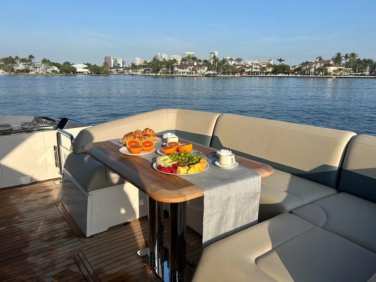 The aft deck features a cozy dining area with a table set for breakfast, offering a serene view of the water and shoreline. aboard FAIRLINE SQUADRON Yacht for Sale