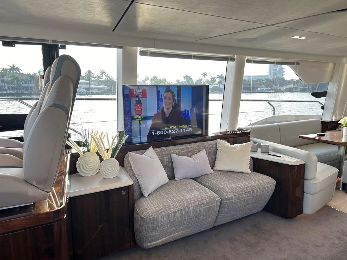 The yacht's interior features a cozy seating area with a television and large windows offering scenic views. aboard FAIRLINE SQUADRON Yacht for Sale