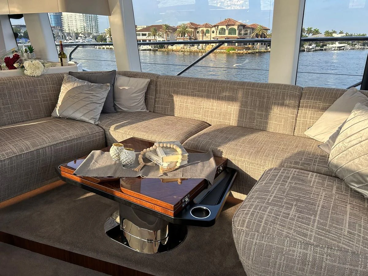 The salon features a comfortable and stylish seating area with a view of the water through large windows. aboard FAIRLINE SQUADRON Yacht for Sale