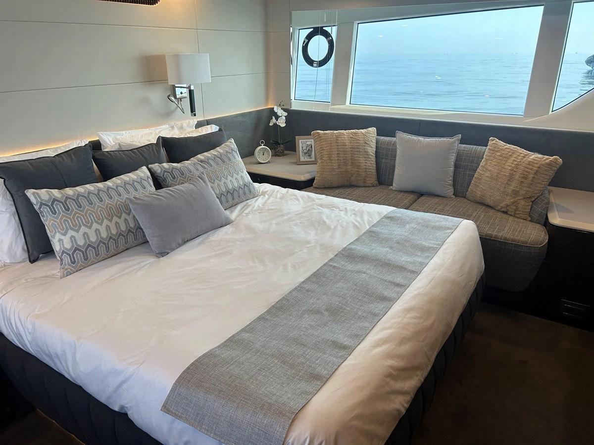 A luxurious stateroom featuring a large bed, elegant decor, and a scenic ocean view through the window. aboard FAIRLINE SQUADRON Yacht for Sale