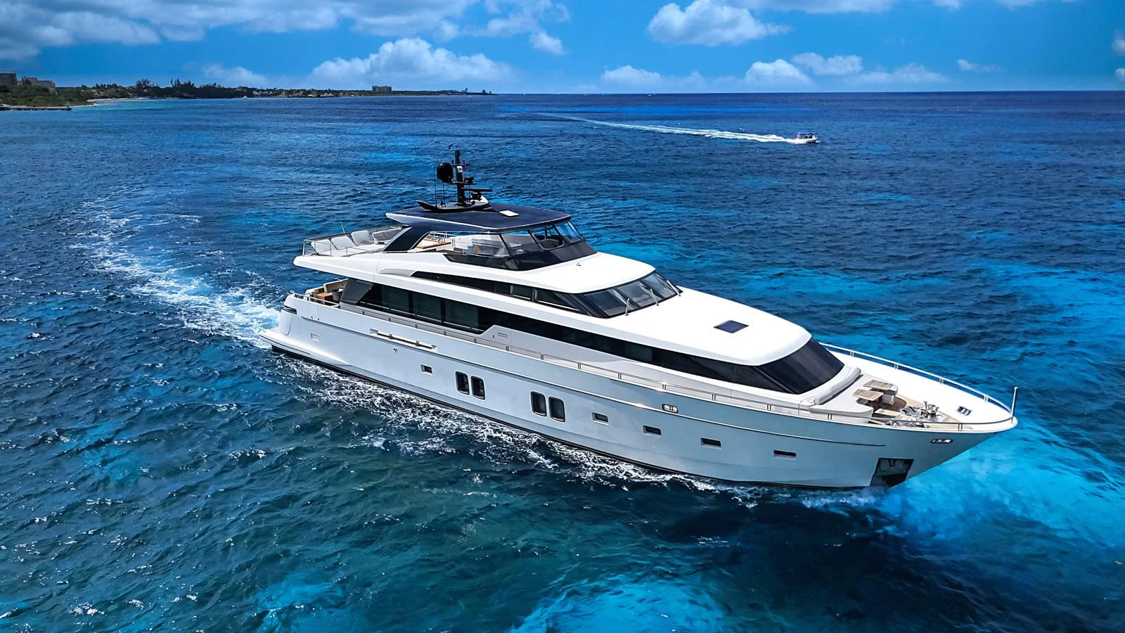 A sleek, modern yacht cruises through clear blue waters under a bright sky. aboard PERCAL Yacht for Sale