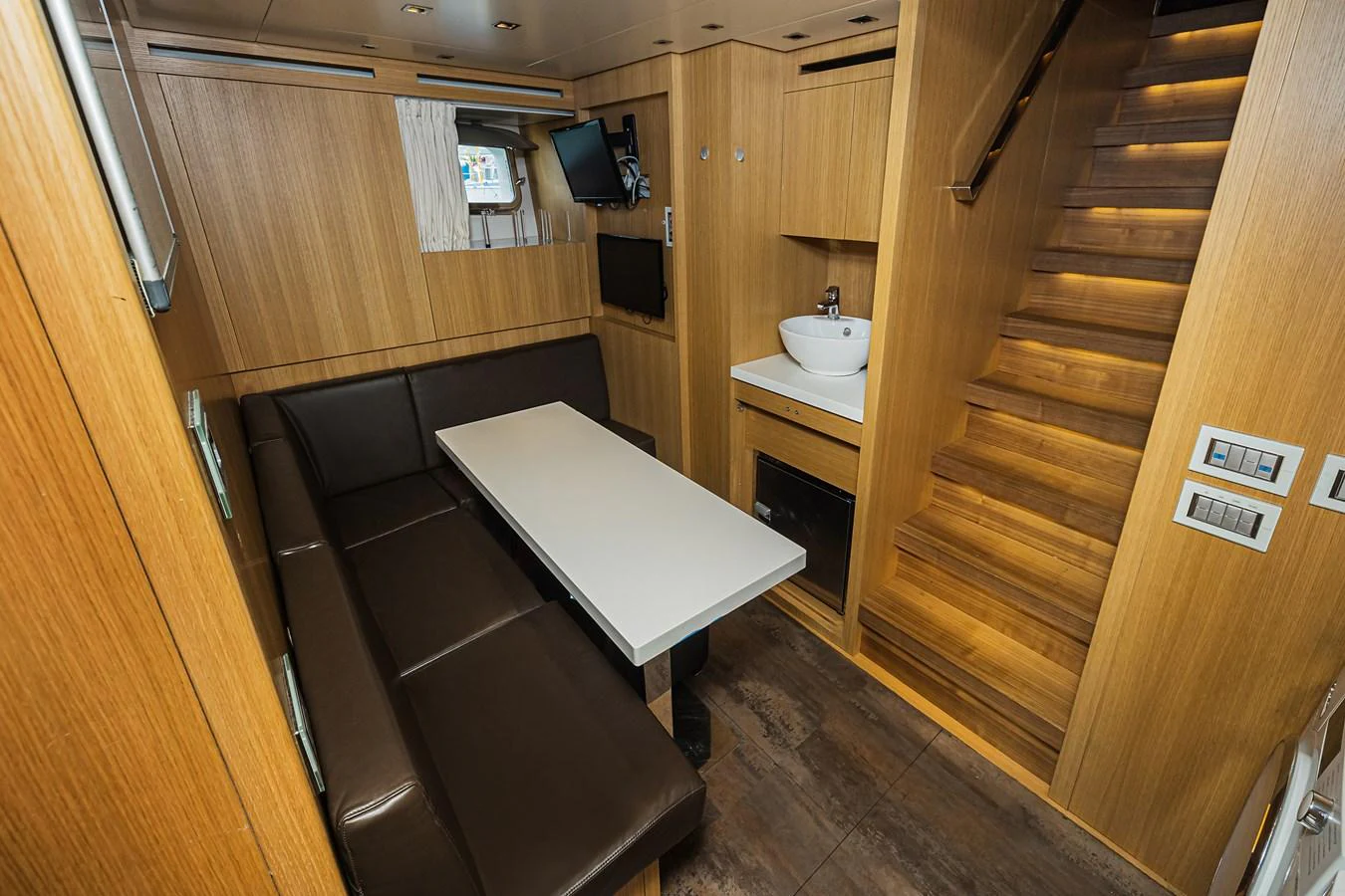 The yacht's interior features a cozy dining area with a sleek table and comfortable seating. aboard PERCAL Yacht for Sale