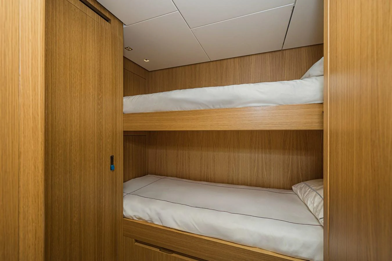 The cozy bunk room features two neatly made beds with wooden paneling and soft lighting. aboard PERCAL Yacht for Sale