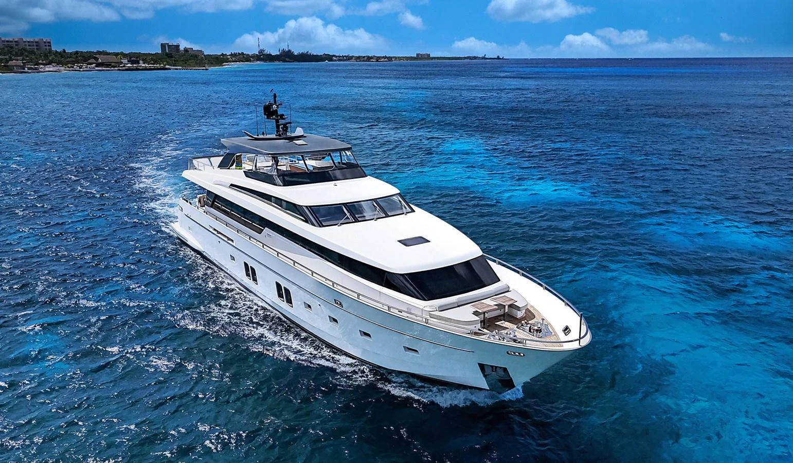 A sleek and modern yacht cruises through clear blue waters under a bright sky. aboard PERCAL Yacht for Sale