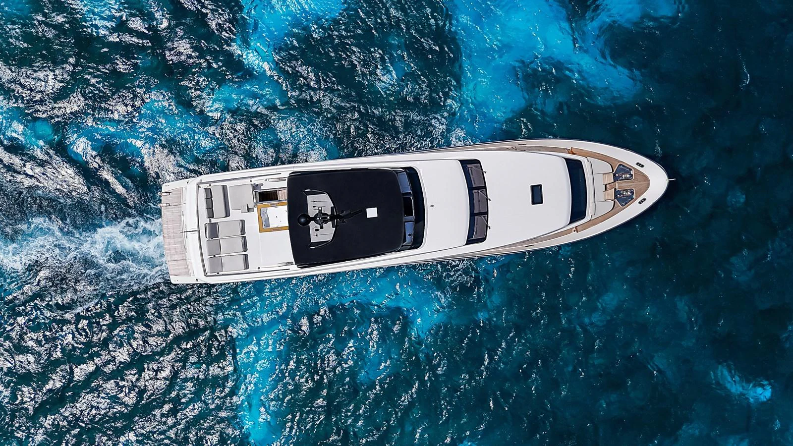 A sleek yacht cruises through vibrant blue waters, showcasing its elegant design from an aerial perspective. aboard PERCAL Yacht for Sale