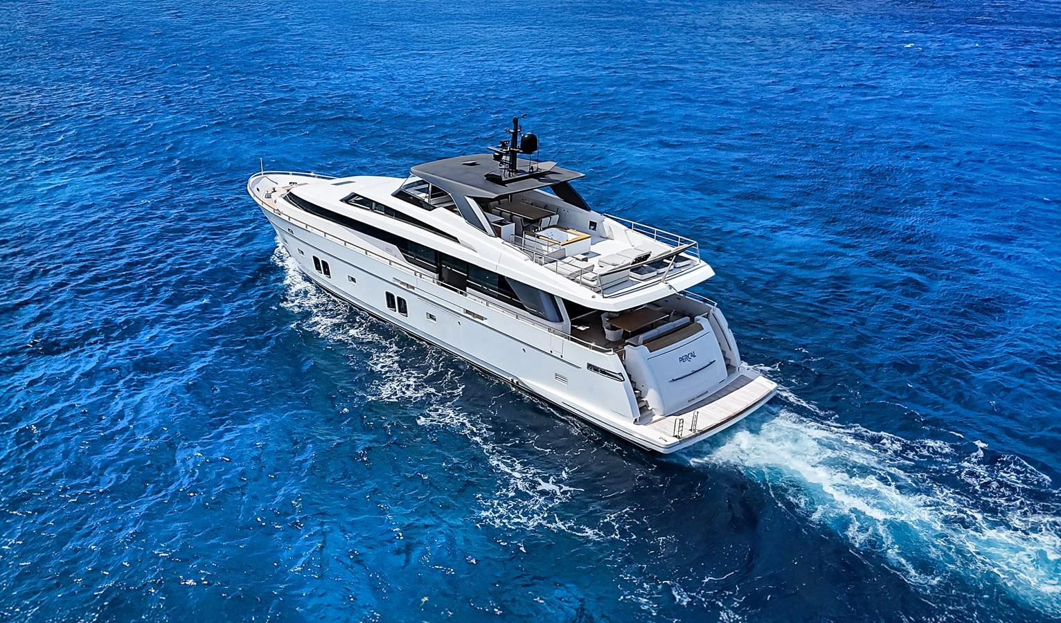 A sleek and modern yacht cruises through clear blue waters, showcasing its elegant design and spacious deck areas. aboard PERCAL Yacht for Sale