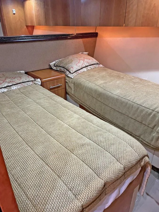 A cozy twin stateroom featuring two single beds with plush bedding and warm wood accents. aboard HATTERAS 68 CONVERTIBLE Yacht for Sale