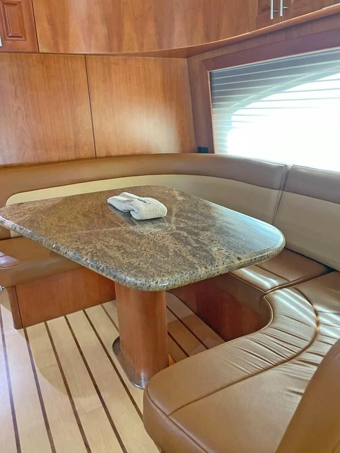 The yacht's interior features a cozy dining area with a polished wooden table and comfortable seating. aboard HATTERAS 68 CONVERTIBLE Yacht for Sale
