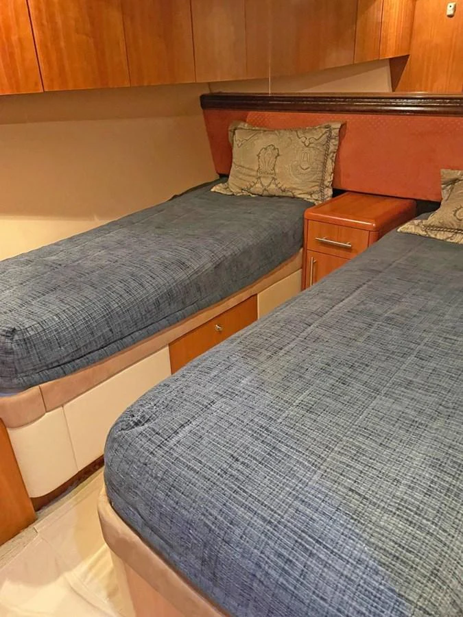 The twin stateroom features two comfortable beds with elegant bedding and ample storage space. aboard HATTERAS 68 CONVERTIBLE Yacht for Sale