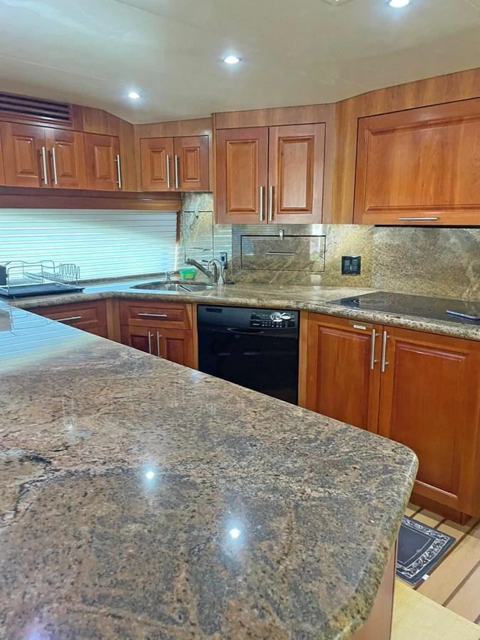 The yacht's galley features rich wooden cabinetry and polished stone countertops, creating a warm and inviting space for culinary activities. aboard HATTERAS 68 CONVERTIBLE Yacht for Sale
