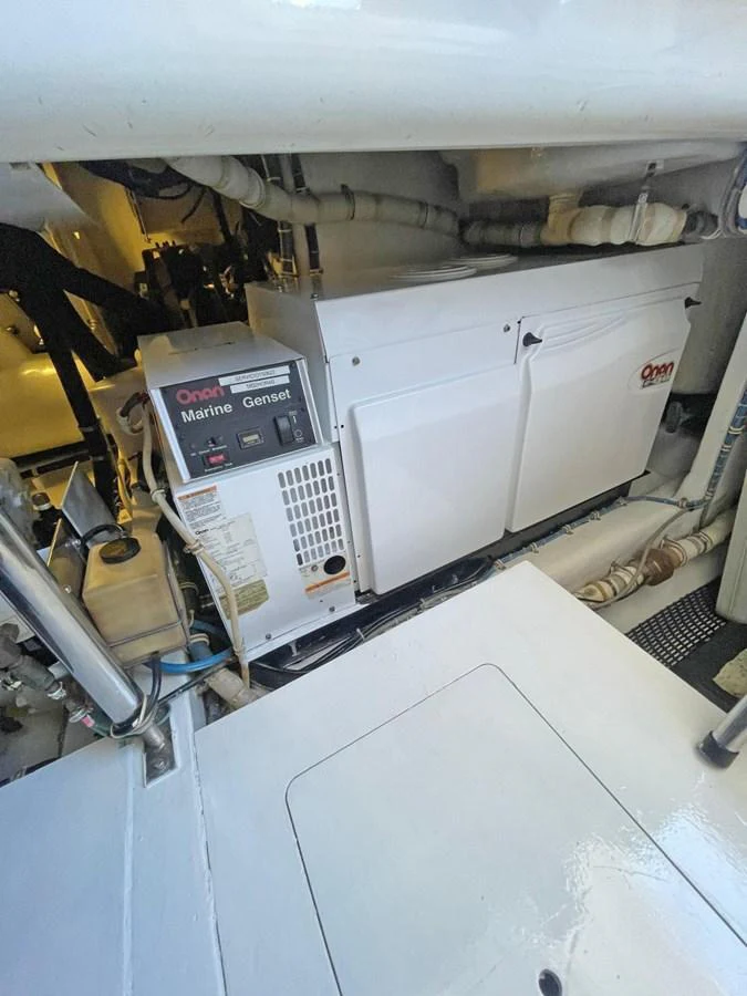 The image showcases the engine room with a marine generator and various mechanical components. aboard HATTERAS 68 CONVERTIBLE Yacht for Sale