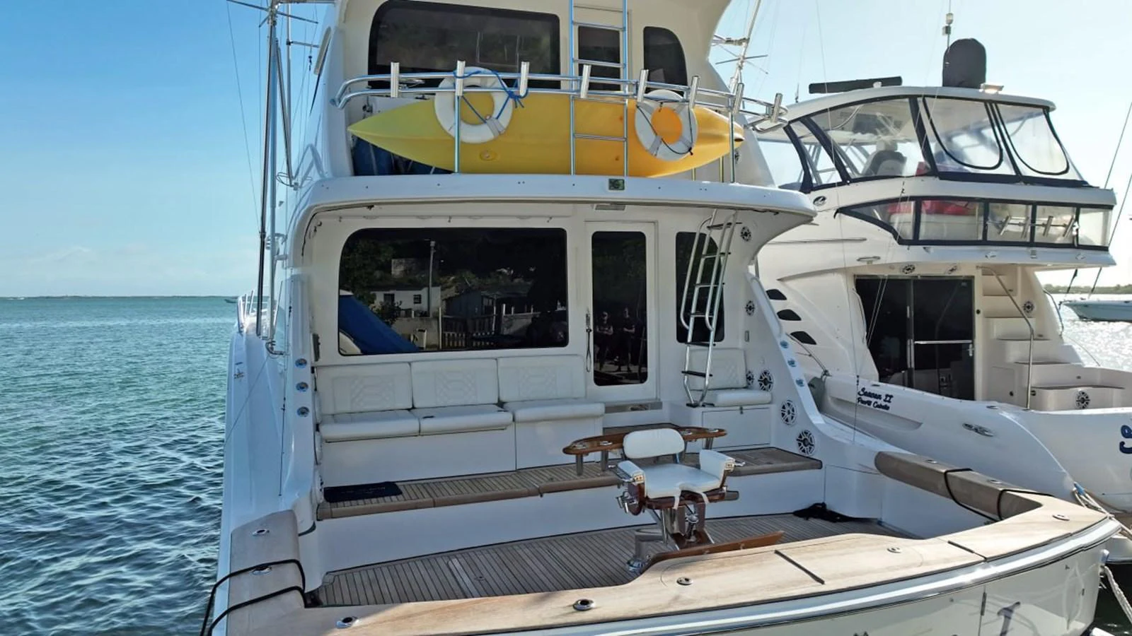 The yacht's aft deck features a spacious seating area and a mounted table, perfect for outdoor relaxation and dining. aboard HATTERAS 68 CONVERTIBLE Yacht for Sale