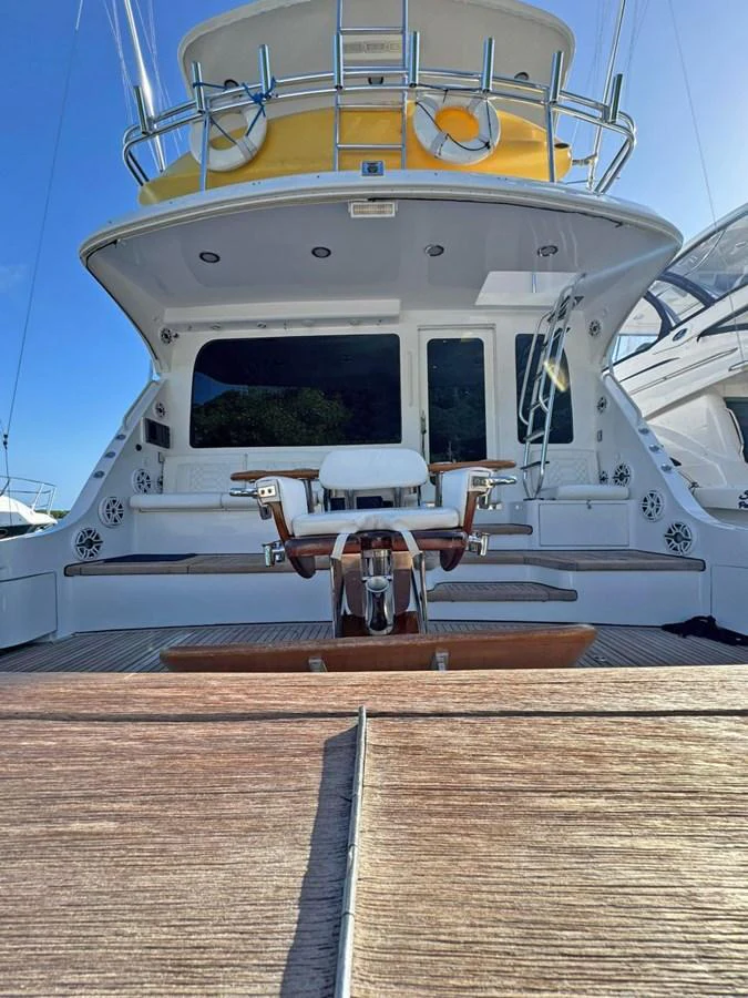 The aft deck features a comfortable seating area with a central fishing chair, perfect for relaxation and sport. aboard HATTERAS 68 CONVERTIBLE Yacht for Sale