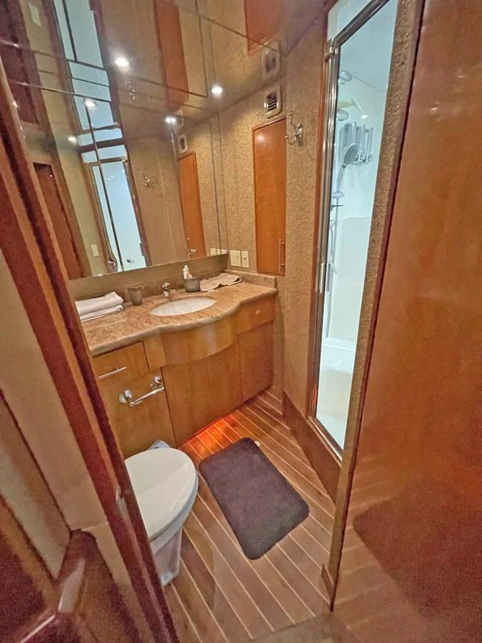 A well-appointed yacht bathroom featuring a sleek vanity and a glass-enclosed shower. aboard HATTERAS 68 CONVERTIBLE Yacht for Sale