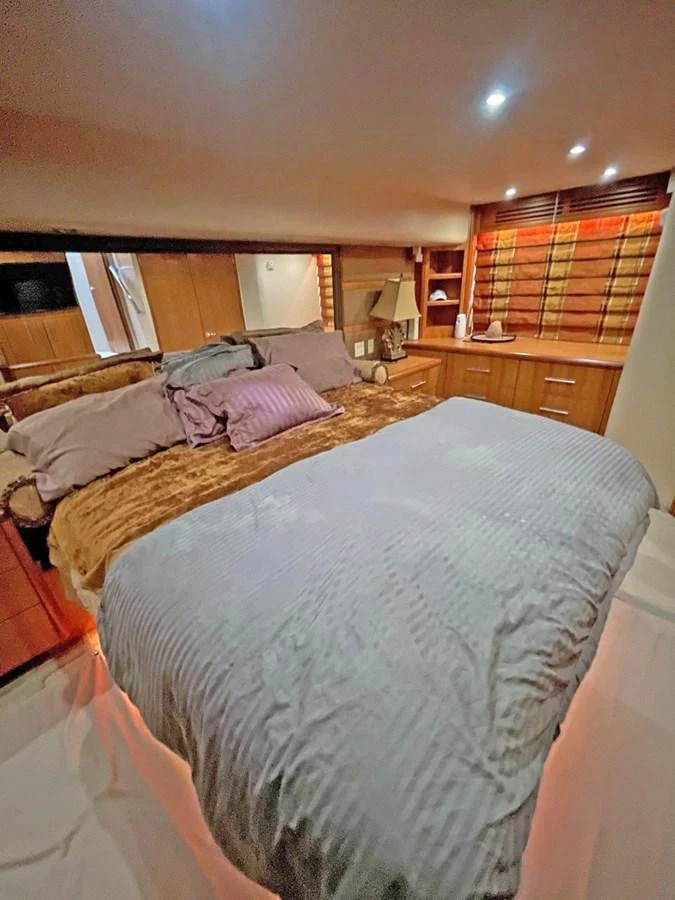 The stateroom features a cozy bed with plush bedding and warm lighting. aboard HATTERAS 68 CONVERTIBLE Yacht for Sale