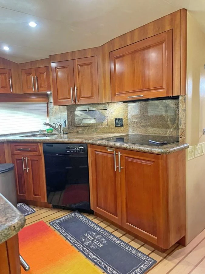 The galley features rich wooden cabinetry, modern appliances, and elegant granite countertops. aboard HATTERAS 68 CONVERTIBLE Yacht for Sale