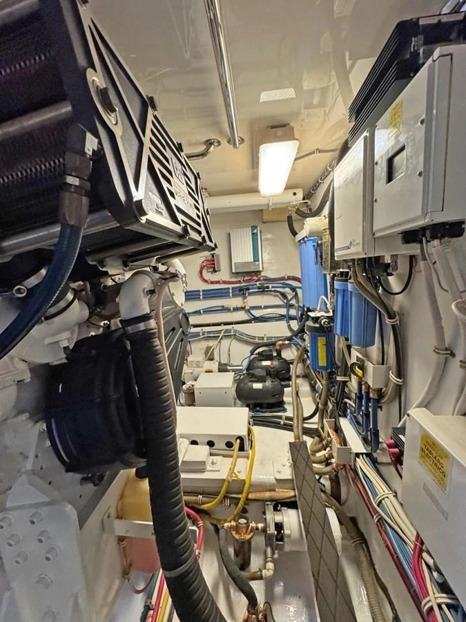 The image showcases the yacht's well-maintained engine room with various technical components and machinery. aboard HATTERAS 68 CONVERTIBLE Yacht for Sale
