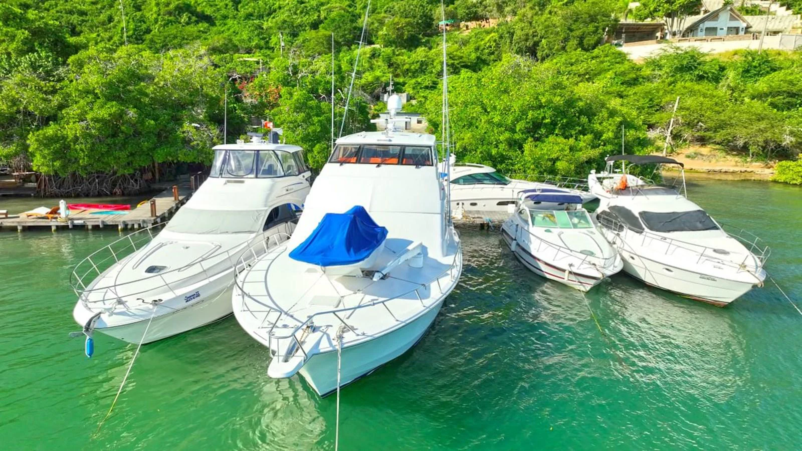 A fleet of yachts is docked in a serene, lush green marina. aboard HATTERAS 68 CONVERTIBLE Yacht for Sale