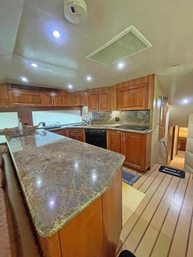 The galley features rich wooden cabinetry and a spacious countertop, creating a warm and inviting atmosphere. aboard HATTERAS 68 CONVERTIBLE Yacht for Sale