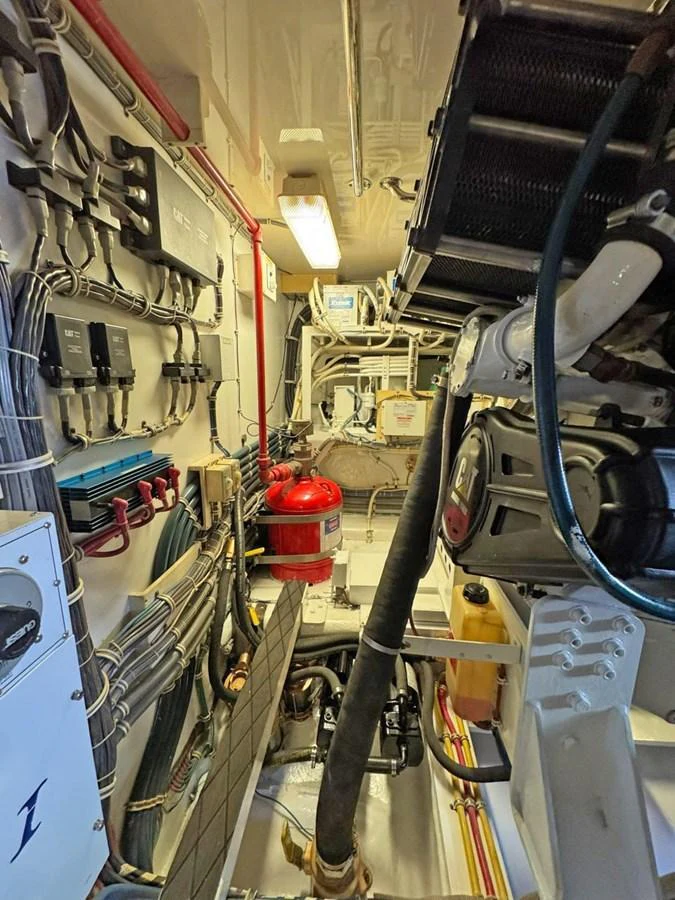 The image showcases the yacht's engine room with various mechanical components and safety equipment. aboard HATTERAS 68 CONVERTIBLE Yacht for Sale