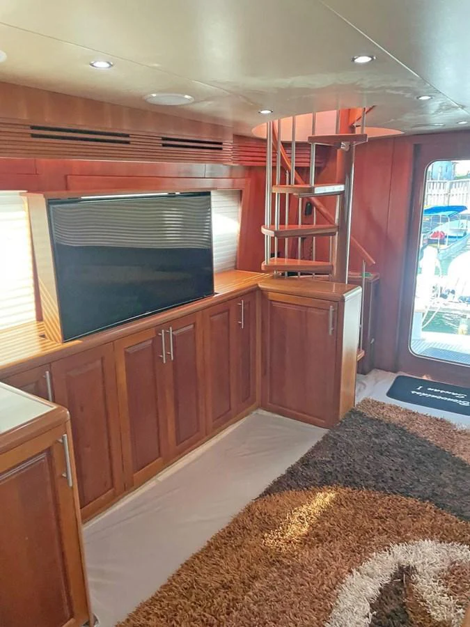 The yacht's interior features a cozy living area with wooden cabinetry and a spiral staircase. aboard HATTERAS 68 CONVERTIBLE Yacht for Sale