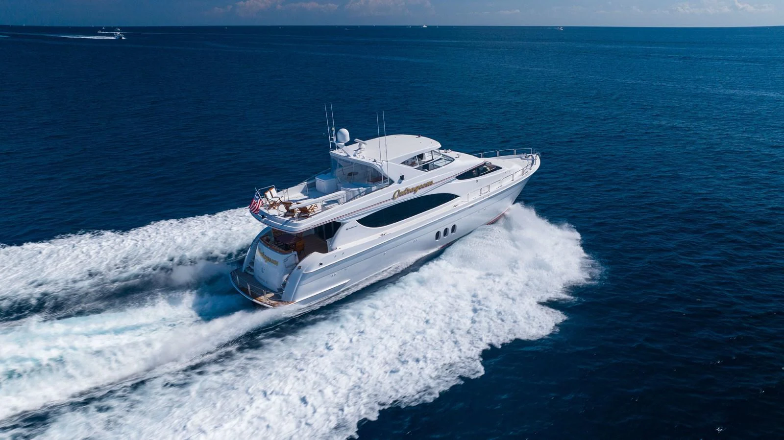 A sleek yacht cruises swiftly through the open sea, leaving a trail of white wake behind. aboard OUTRAGEOUS Yacht for Sale