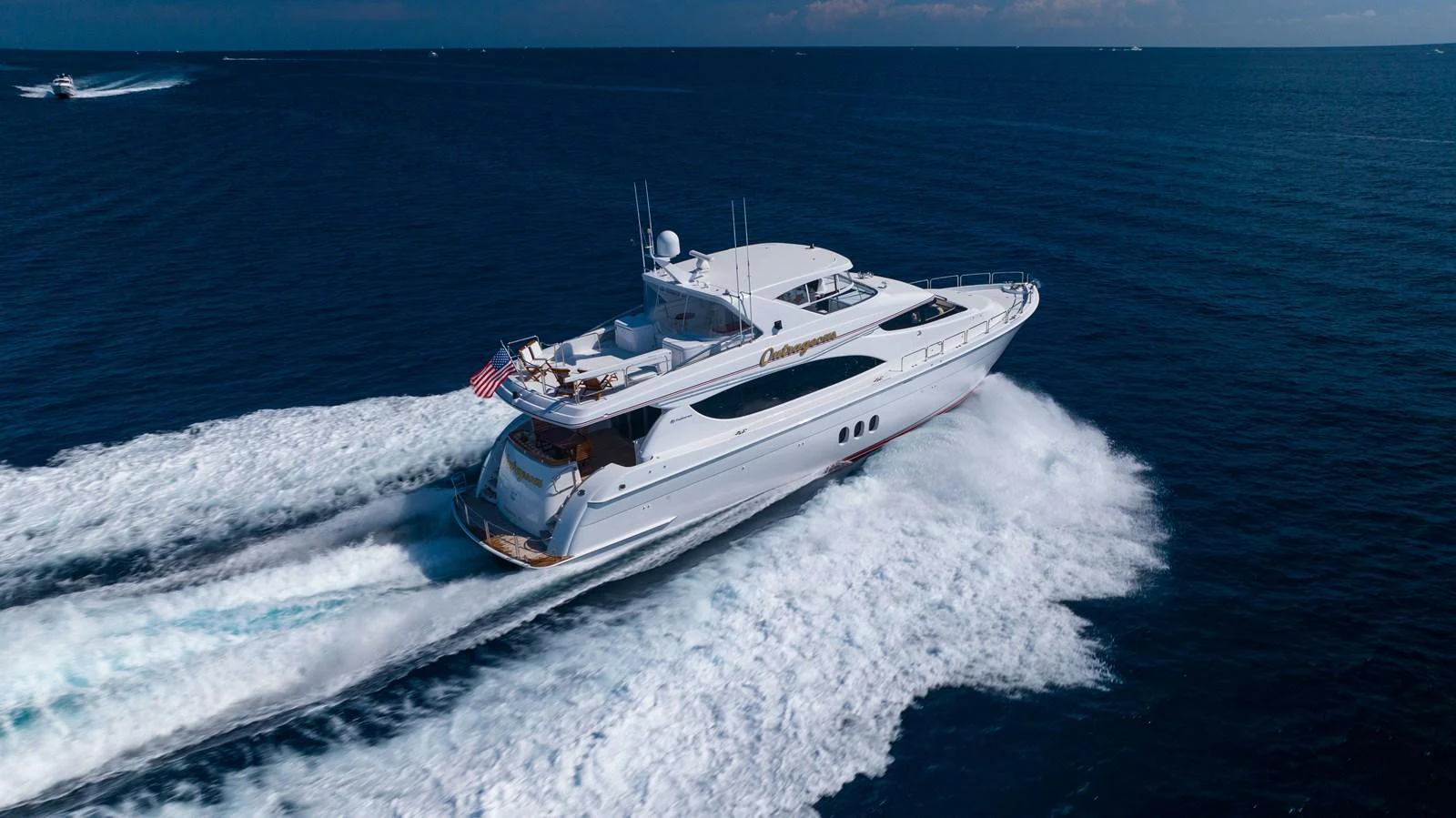 A sleek yacht cruises swiftly through the open sea, leaving a trail of white wake behind. aboard OUTRAGEOUS Yacht for Sale