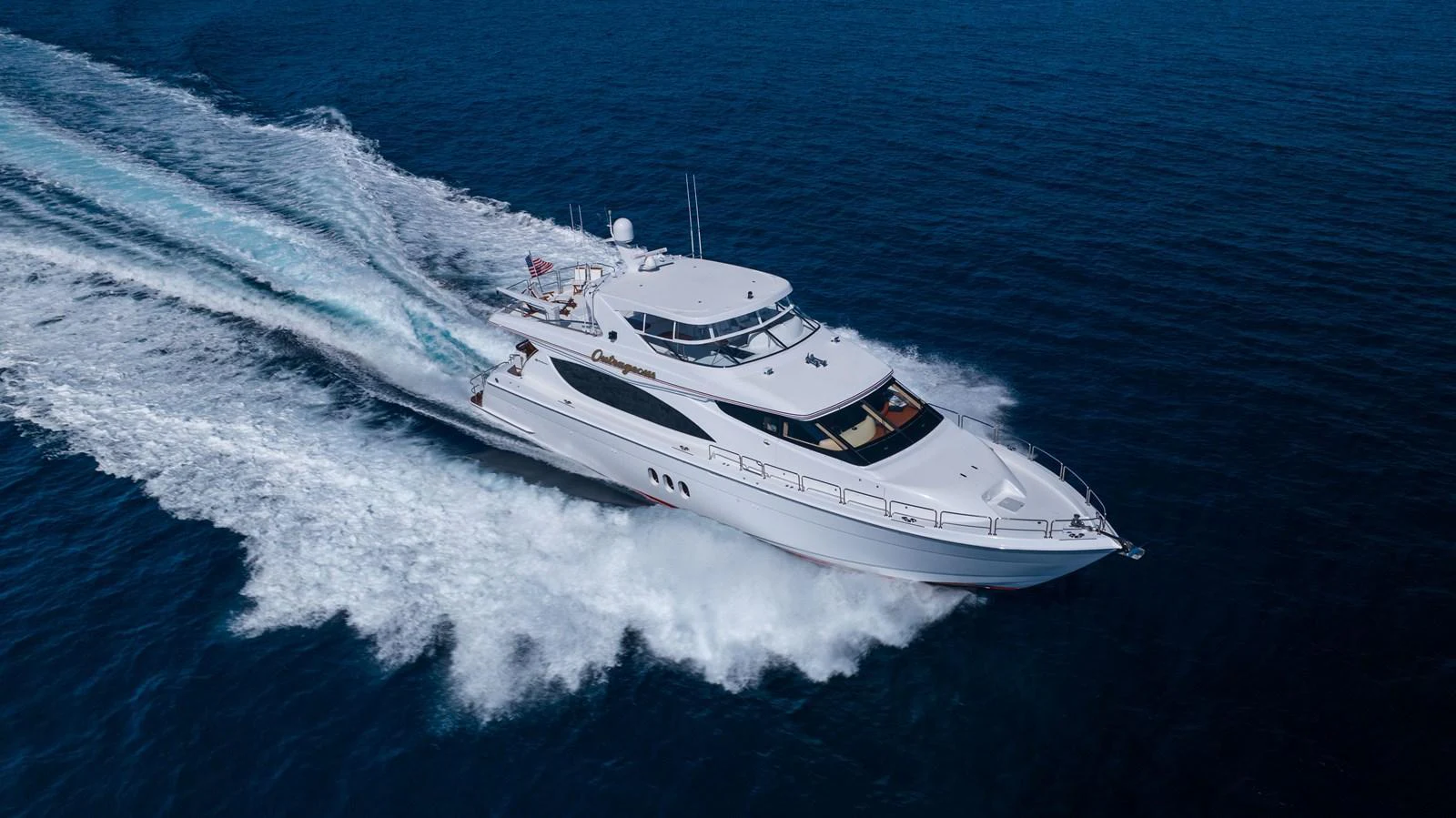 A sleek yacht cruises swiftly through the open sea, leaving a trail of white wake behind. aboard OUTRAGEOUS Yacht for Sale