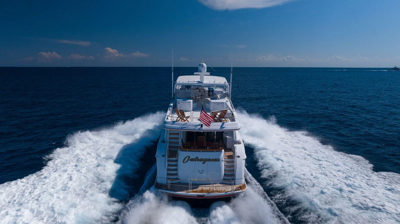 A luxurious yacht cruises through the open sea, leaving a trail of white waves behind. aboard OUTRAGEOUS Yacht for Sale