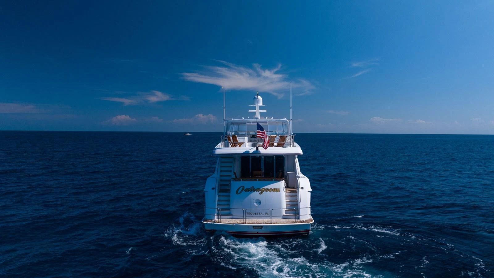 A luxurious yacht cruising on the open sea under a clear blue sky. aboard OUTRAGEOUS Yacht for Sale