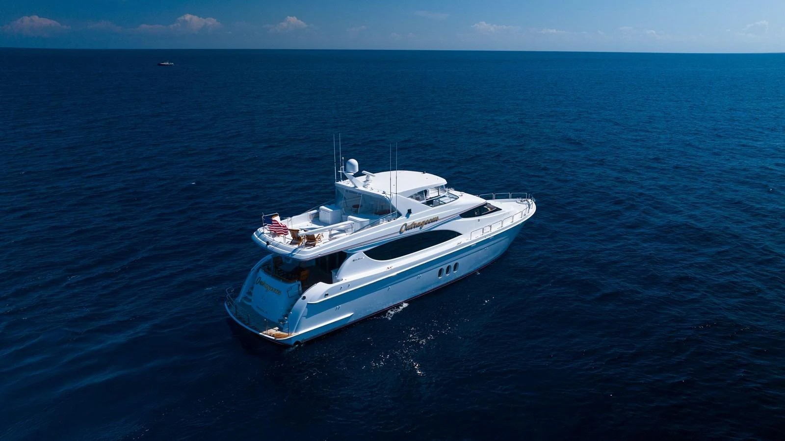 A luxurious yacht cruising on the open sea under a clear blue sky. aboard OUTRAGEOUS Yacht for Sale