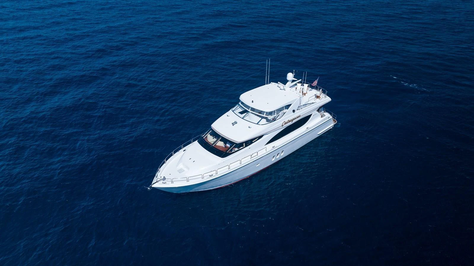 A sleek yacht glides gracefully over the deep blue sea, showcasing its elegant design. aboard OUTRAGEOUS Yacht for Sale
