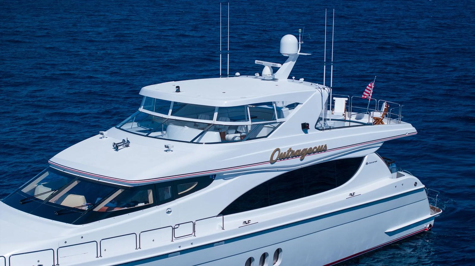 A sleek and modern yacht cruising on the open sea with a pristine white exterior and elegant design. aboard OUTRAGEOUS Yacht for Sale