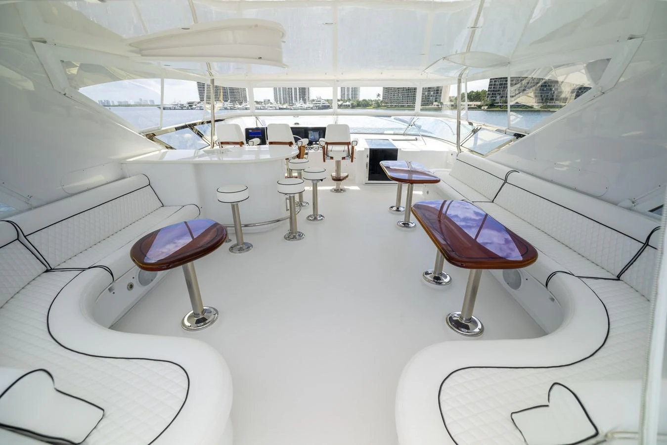 The flybridge features elegant seating with polished wooden tables and panoramic views. aboard OUTRAGEOUS Yacht for Sale
