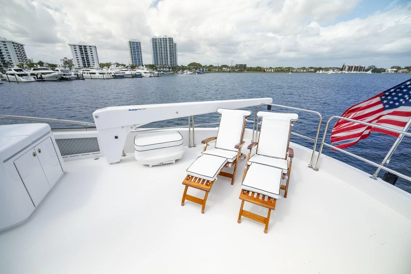 The sundeck offers a serene space with lounge chairs and a view of the marina. aboard OUTRAGEOUS Yacht for Sale